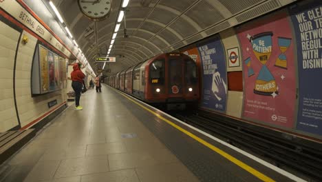 Tren-Subterráneo-De-Londres-Con-Amapola-De-Recuerdo-Que-Se-Detiene-En-La-Estación-Verde-Bethnal-Casi-Vacía