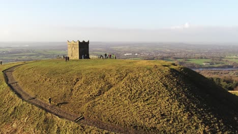 Rivington-tower-fell-runners-on-summit-Lancashire-reservoir-hiking-countryside-aerial-view-orbit-left