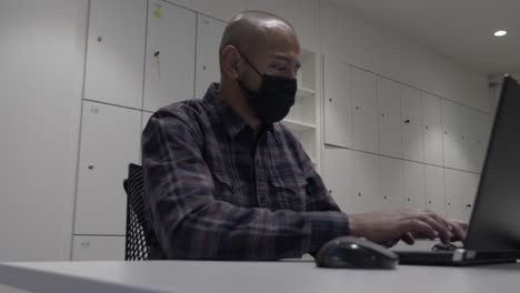 Erwachsener-Mann,-Der-Im-Büro-Arbeitet-Und-Gesichtsmaske-Mit-Laptop-Trägt
