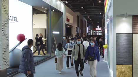 People-wearing-masks-and-walking-in-between-product-pavilions-at-kitchen-design-exhibition-in-China,-during-COVID-19-Pandemic