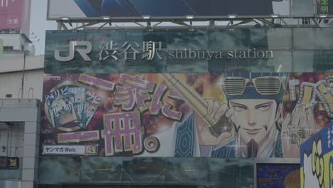 Letrero-De-La-Estación-De-Shibuya-De-La-Línea-Jr-Y-Anuncios-Publicitarios-En-La-Pared-Del-Edificio-De-La-Plaza-Hachiko-En-Tokio,-Japón