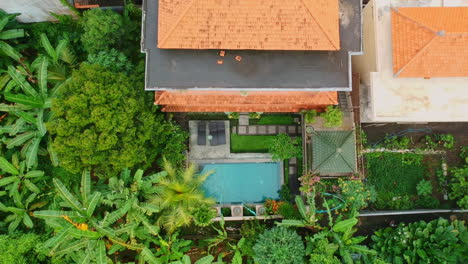 Aerial-top-down-view-rising-high-above-stunning-mansion-with-pool-and-huge-tropical-garden-in-Ubud,-Bali,-Indosnesia