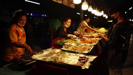 Comida-Callejera-Asiática---La-Vendedora-Tailandesa-Detrás-Del-Mostrador-Pone-Comida-Al-Comprador