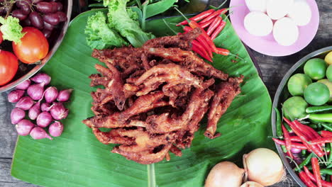 Top-down-view-Fried-chicken-feet-displayed-on-banana-leaf,-table-full-of-Vegetables