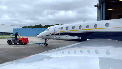 Modern-luxury-private-jet-being-towed-out-of-a-hangar,-view-from-the-wings