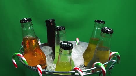 3-3-Loop-Green-Screen-Rotierender-Metallischer-Partyeimer-Mit-Kohlensäurehaltigen-Insel-Sodagetränken-In-Eis-Mit-Hängenden-Zuckerstangen-Und-Wassertropfen-Auf-Glasflaschen-Mit-Mango-Ingwer-Ananas-Limetten-Cola-Creme
