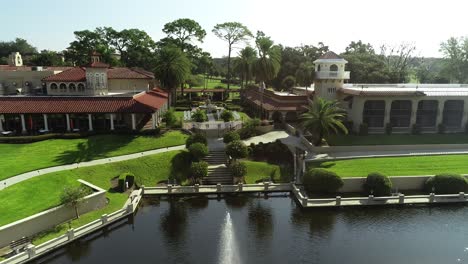 Aerial-View-of-Chairs-Set-Up-for-Wedding-Ceremony-Overlooking-a-Lake-With-a-Fountain-at-Luxury-Resort-on-a-Sunny-Day-in-Florida