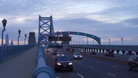 Panorama-Of-Philadelphia-Skyline,-Ben-Franklin-Bridge-At-Sunset-As-Cars-and-Trucks-drive-By---static-shot