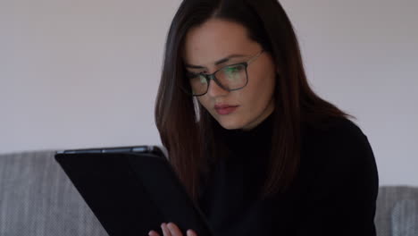 Handheld-shot-of-a-focused-young-woman-working-on-a-tablet