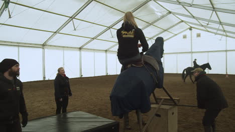 Woman-thrown-off-mechanical-bucking-horse-onto-padded-stunt-mat-in-rehearsal
