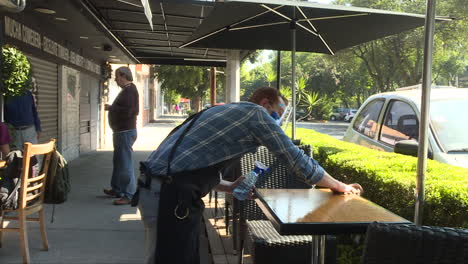 waitress-sanitizing-and-cleaning-table-in-a-coffee-shop-outdoors