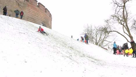 Children-sledding-down-a-snowy-Burcht-in-Leiden,-the-Netherlands-during-the-pandemic