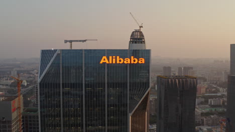 Close-pivot-around-logo-of-Alibaba-group-on-top-of-their-Guangzhou-headquarters-office-building-at-sunset