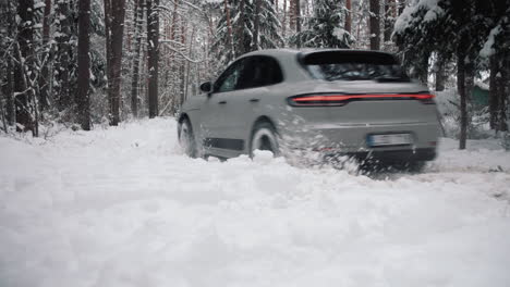 Grey-Porsche-Macan-car-driving-thrugh-deep-snow-in-forest