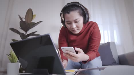 Freelance-woman-redshirt-using-tablet-with-headphone-for-meeting-online-at-home
