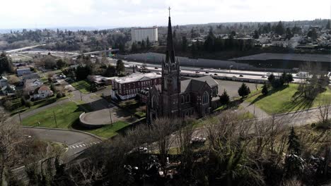 Katholische-Kirche-Des-Heiligen-Rosenkranzes,-Innenstadt-Von-Tacoma-Im-Hintergrund,-Luftbahn
