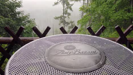 Hail-falling-on-a-beer-table-in-mountain-bar-with-forest-background