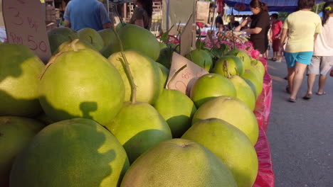 Footage-of-display-pomelos-on-the-side-road,-with-sun-light-and-shadow-of-people-passing-by