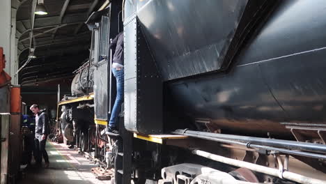 Teenage-boy-climbs-in-and-out-of-locomotive-steam-train-engine-drivers-cab