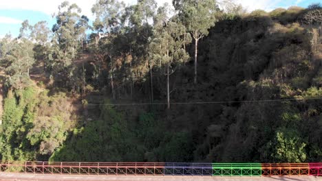 Dron-pass-colored-bridge-of-Guambi-towards-trees-on-Ecuador