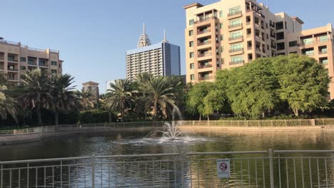 Wide-landscape-view-of-a-lake-with-fountain-and-buildings-as-background-during-broad-daytime
