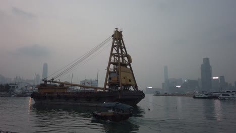 Slow-Pan-Sampan-passing-Container-ship-in-Victoria-Harbour,-Hong-Kong