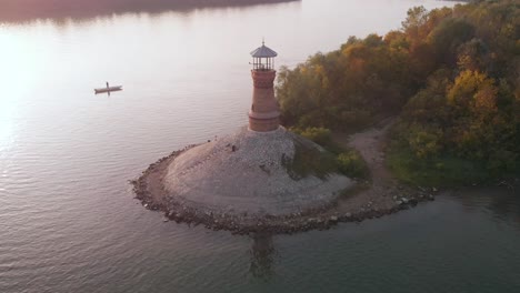 Orbiting-footage-around-the-old-stone-lighthouse-on-the-Danube-river-with-sunset-in-the-background-and-amazing-autumn-colors-on-the-forest