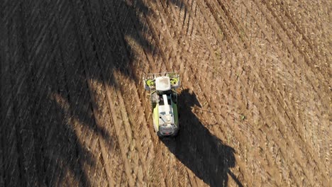 4K-top-down-aerial-view-of-a-harvester-driving-through-a-cornfield-after-harvest-is-finished