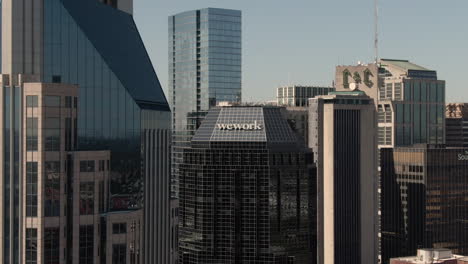 Aerial-reveal-of-Wework-logo-on-top-of-high-rise-building-in-downtown-Nashville,-Tennessee-on-a-clear,-fall-day