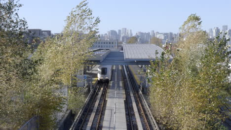 Train-Moving-Through-The-Railways-In-Vancouver,-Canada-With-Green-Trees-and-Large-Buildings---Steady-Shot