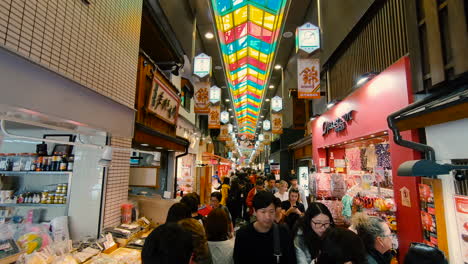 High-angle-footage-of-a-famous-tourist-food-market-with-tourists-walking-at-Kyoto,-Japan