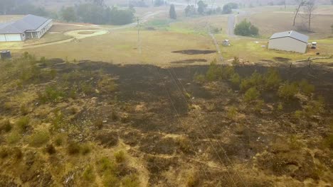 Homes-saved-from-burning-near-the-scorched-burnt-ground-from-bush-fire,-Aerial-drone-flyover-reveal-shot