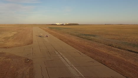 An-air-show-biplane-Pitts-S2B-flying-down-the-runway-takes-off-from-a-small-airport-at-sunrise