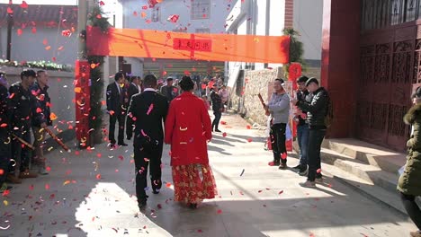 Chinese-wedding-couple-walking-slow-motion-down-street-as-floating-confetti-fireworks-through-scene-behind-them