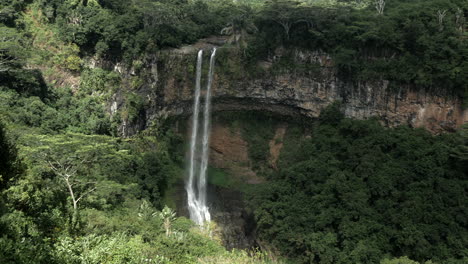Pan-shot-of-giant-deep-waterfall-in-middle-of-forest-jungle,steady