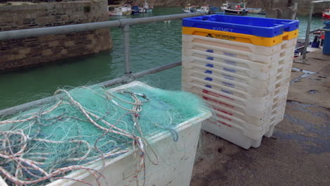 Fischernetze-Und-Kisten-Am-Hafen-Mit-Booten-Im-Hintergrund