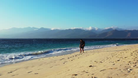 Tourist-woman-with-backpack-just-coming-for-holiday-and-walking-along-exotic-beach-impressed-by-blue-sea-in-Bali