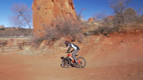 Young-man-jumping-dirt-ramps-on-an-obstacle-course,-with-a-mountain-bike,-in-Colorado-Springs,-Colorado