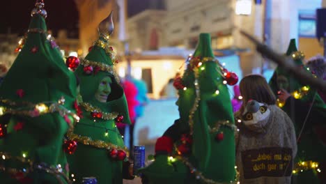 Tres-Personas-Disfrazadas-De-árbol-De-Navidad-Celebrando-Una-Fiesta-Al-Aire-Libre-Durante-La-Noche,-Primer-Plano