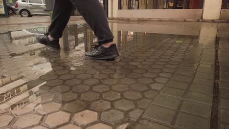 Person-with-black-Newbalance-shoes-walking-through-puddle,-Slow-Motion