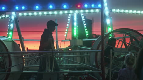 Looper-ride-operator-stopping-ride-at-carnival-in-Pennsylvania-at-dusk,-Slow-Motion