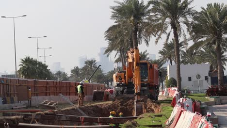 A-crane-digging-the-ground-and-collecting-soil-on-a-dumping-truck-during-Highway-construction--Doha,-Qatar--03-10-2020