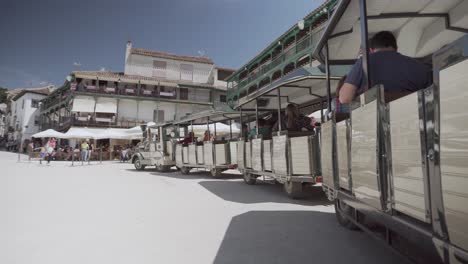 People-Sitting-In-A-Train-At-The-Plaza-Mayor-De-Chinchon-In-Madrid,-Spain---panning-reveal-shot