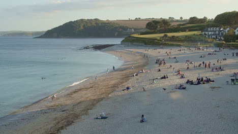 People-enjoy-hours-of-sun-on-Gylly-Beach,-Falmouth,-Cornwall,-wide-high-angle