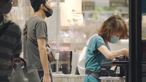Working-Staffs-And-Customers-Wearing-Face-Masks-At-The-Counter-Of-A-Supermarket-With-Plastic-Barrier-In-Kamata,-Tokyo,-Japan-During-The-COVID-19