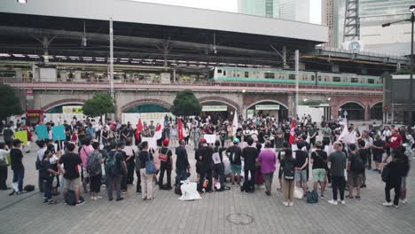 Demonstrators-At-The-Shinbashi-Station-In-Tokyo,-Japan-Protesting-In-Solidarity-With-Hong-Kong---wide-slowmo-shot