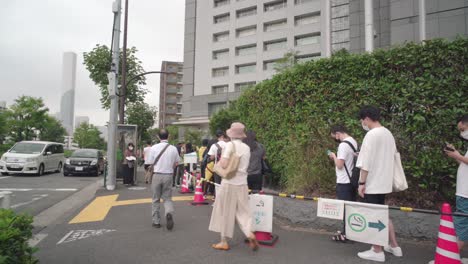 Menschen,-Die-Gesichtsmasken-Tragen,-Stehen-Während-Des-Pandemie-coronavirus-Vor-Dem-Regierungsbüro-Des-Regionalen-Einwanderungsbüros-Von-Tokyo-In-Japan-In-Linie-Mit-Sozialer-Distanzierung