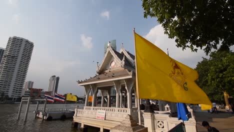 Flag-of-The-King-of-Thailand-flying-beside-Chao-Phraya-River,-Bangkok,-slow-motion
