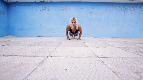 A-young-woman-doing-pushups-on-a-concrete-floor-outdoors