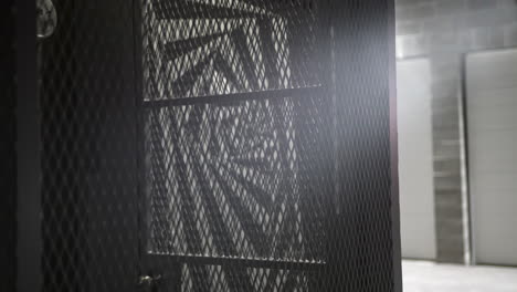 Metal-cage-in-a-dark-city-alley-cars-light-reflection